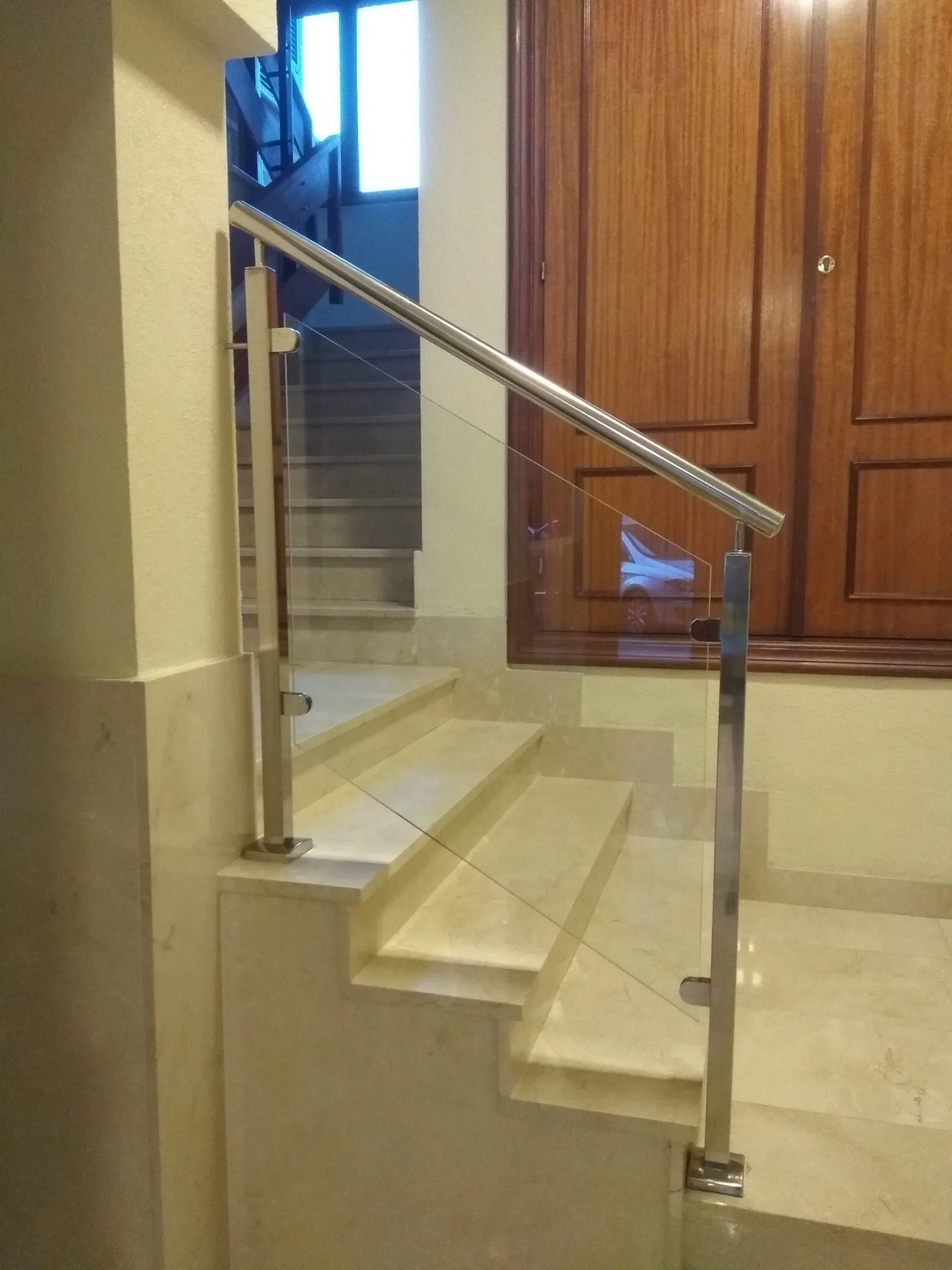 Barandilla acristalada con postes y pasamanos de acero inoxidable en una escalera interior