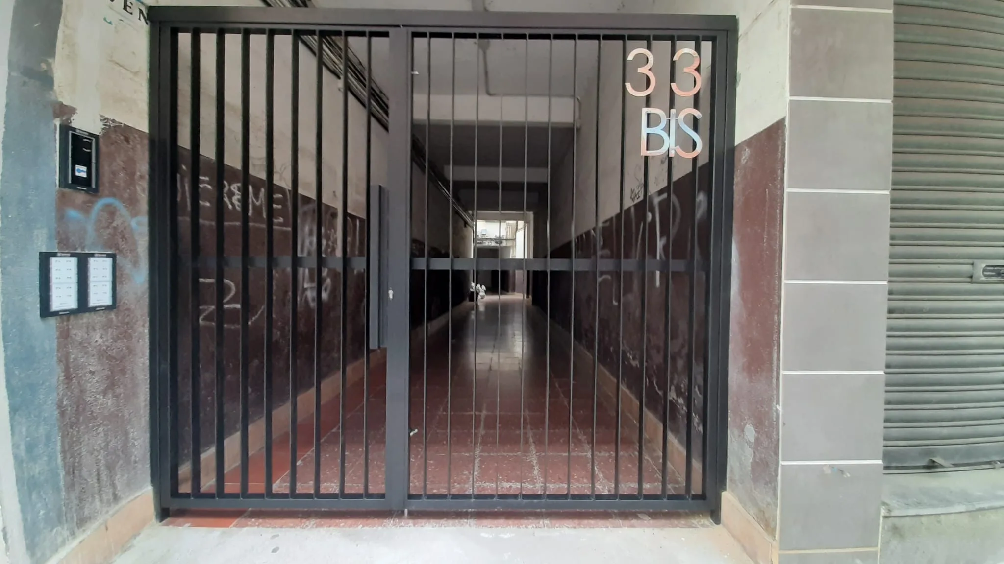 Cierre metálico negro con barrotes verticales en el portal de un edificio
