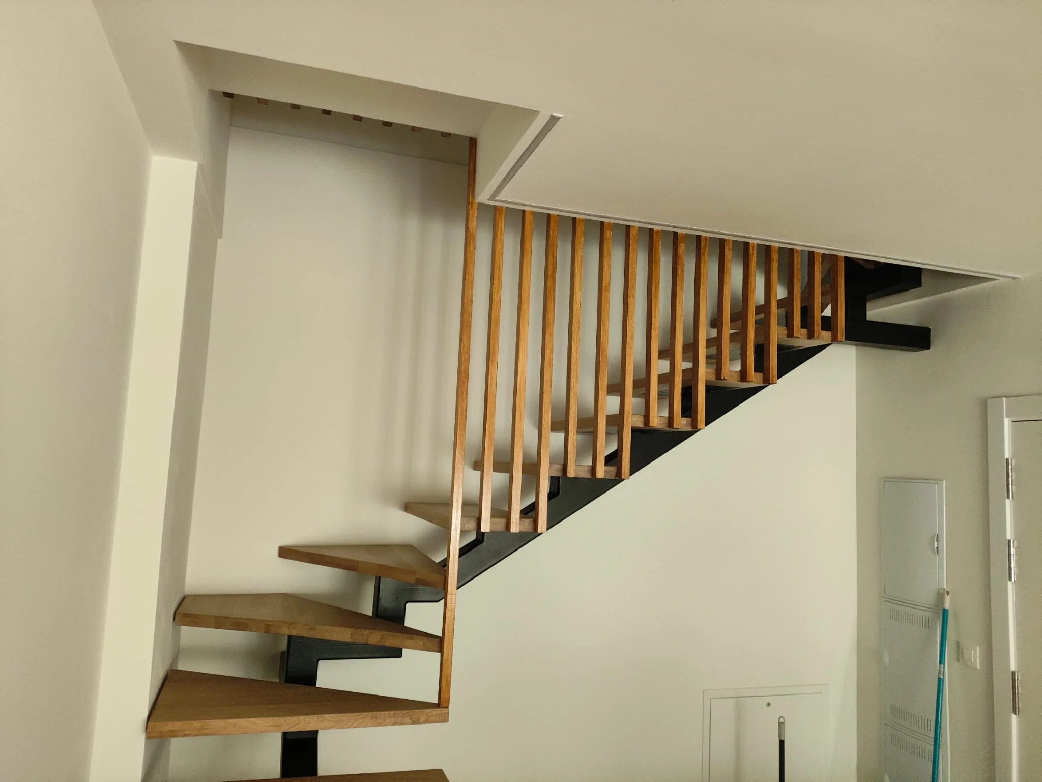 Escalera interior a medida de Talleres Ibarrondo, con zanca metálica negra y peldaños de madera.