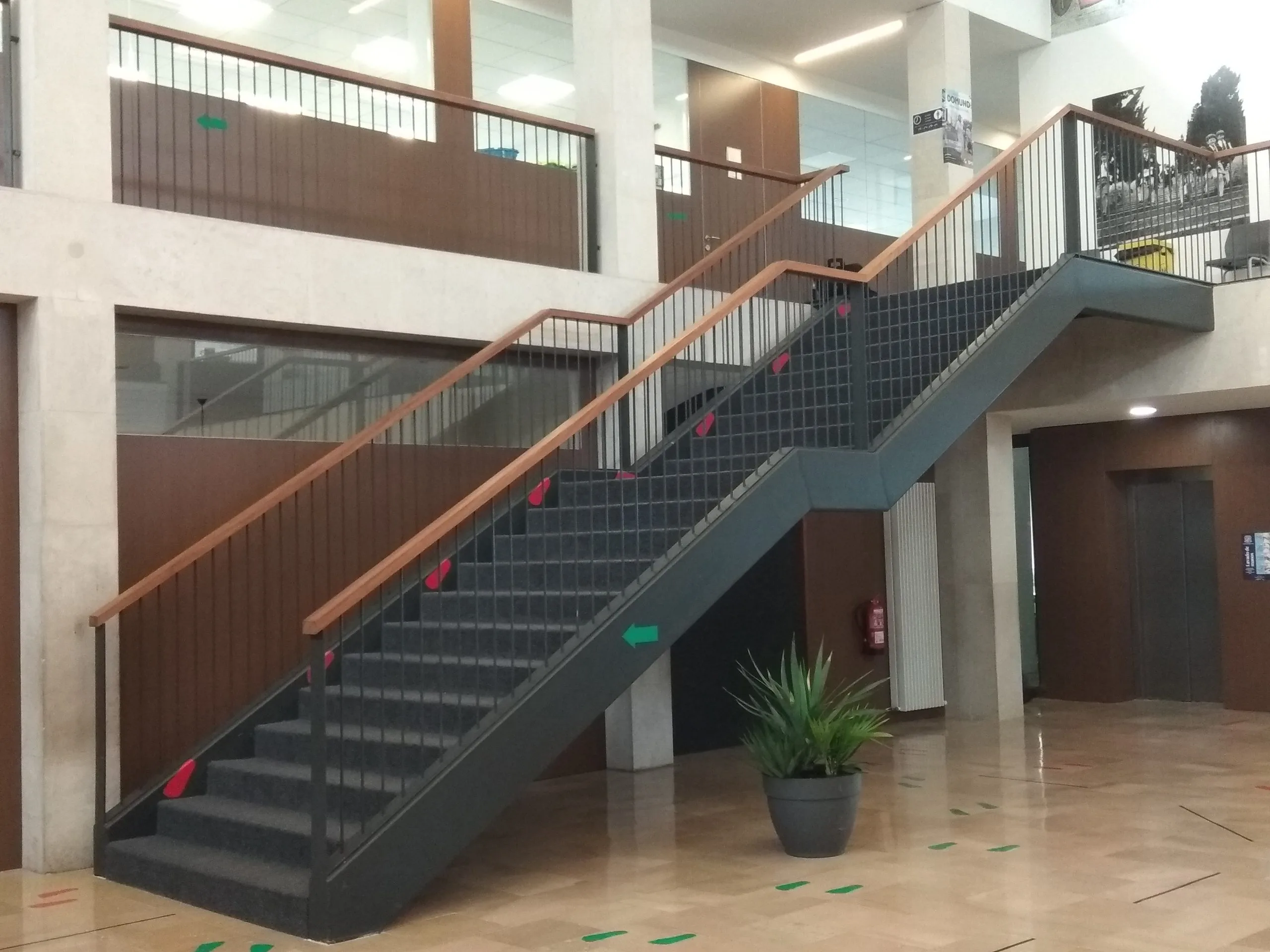 Escalera metálica gris con pasamanos de madera en el vestíbulo de un edificio