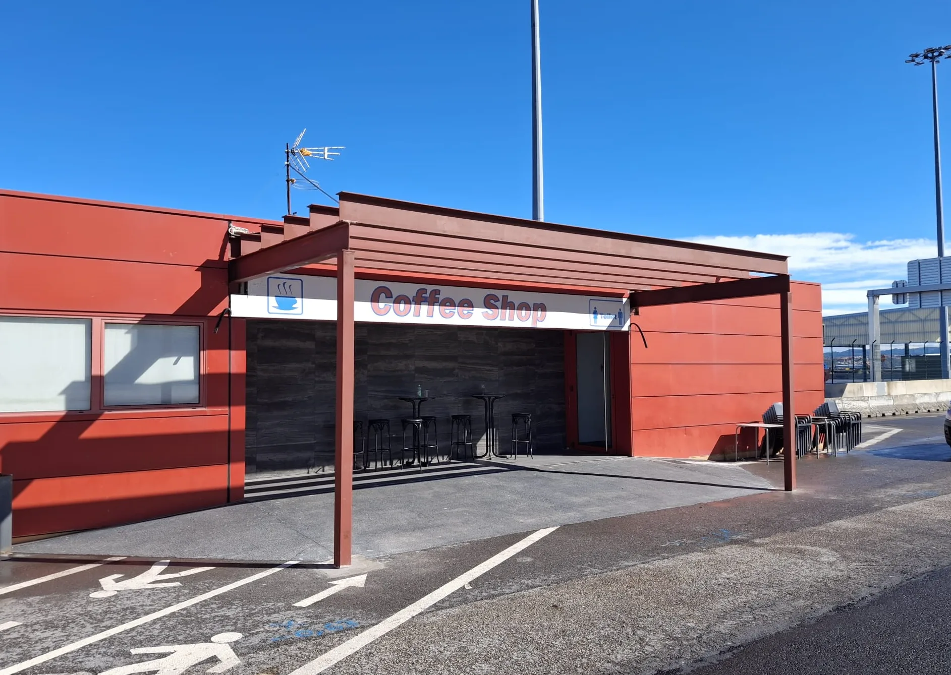 Marquesina metálica frente a la entrada de una nave de fachada roja