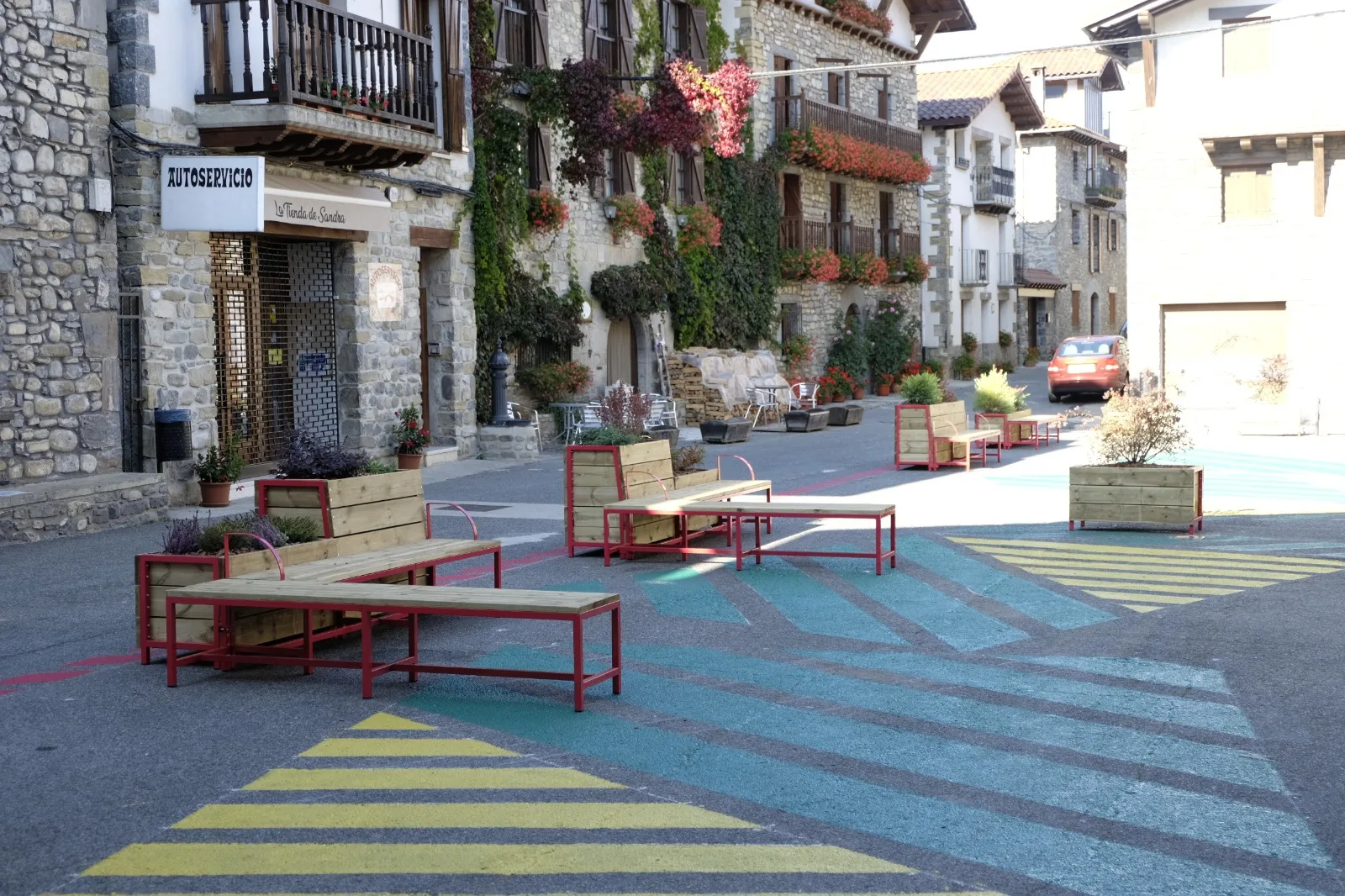 Bancos con estructura metálica roja y asientos de madera en una plaza