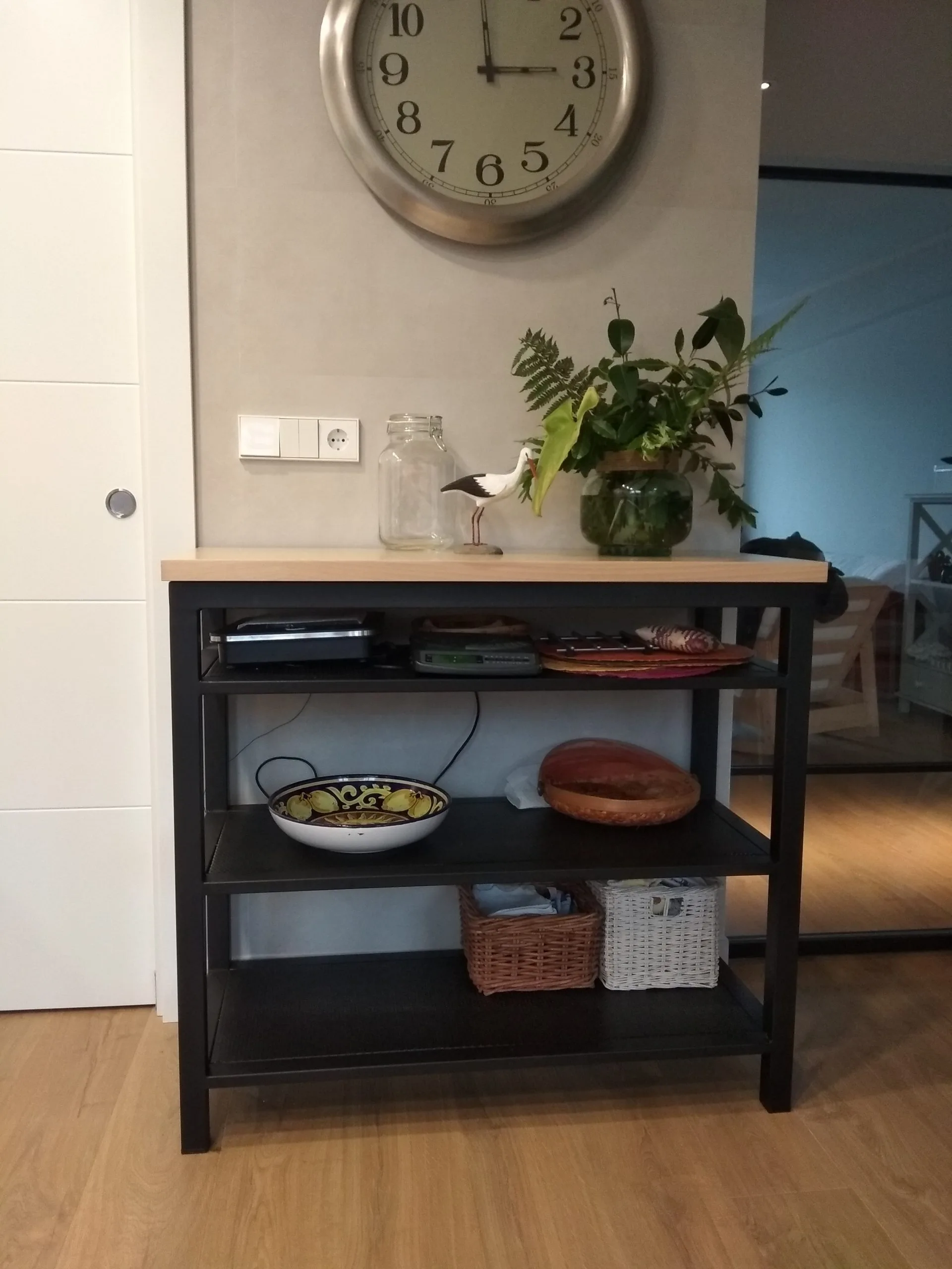 Mueble auxiliar negro con baldas de madera, platos y cuencos
