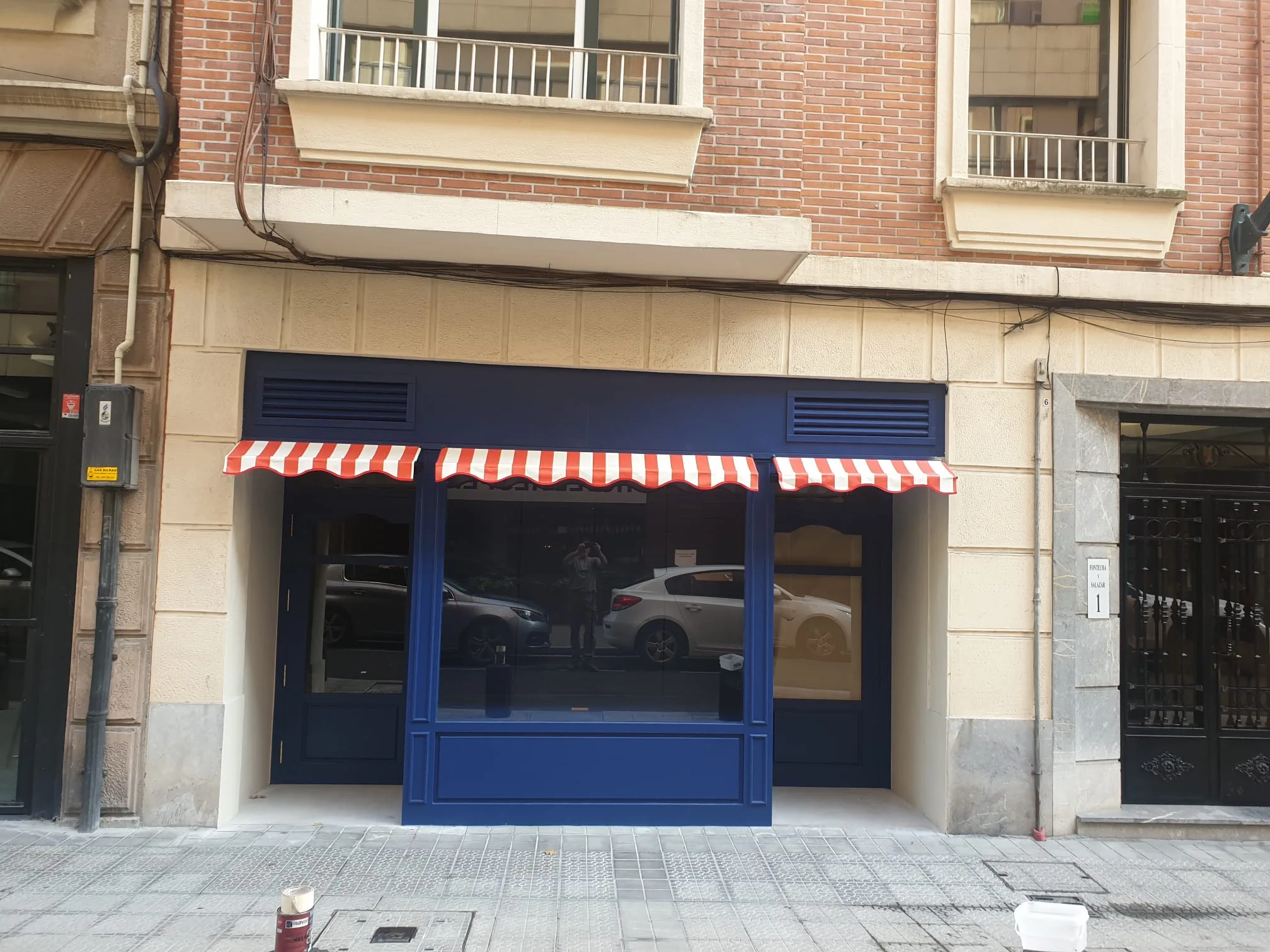 Local con fachada azul y toldo fijo de rayas rojas y blancas